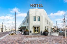 Stylish hotel exterior with a prominent sign, modern architecture, and clear blue sky, set on a cobblestone street.