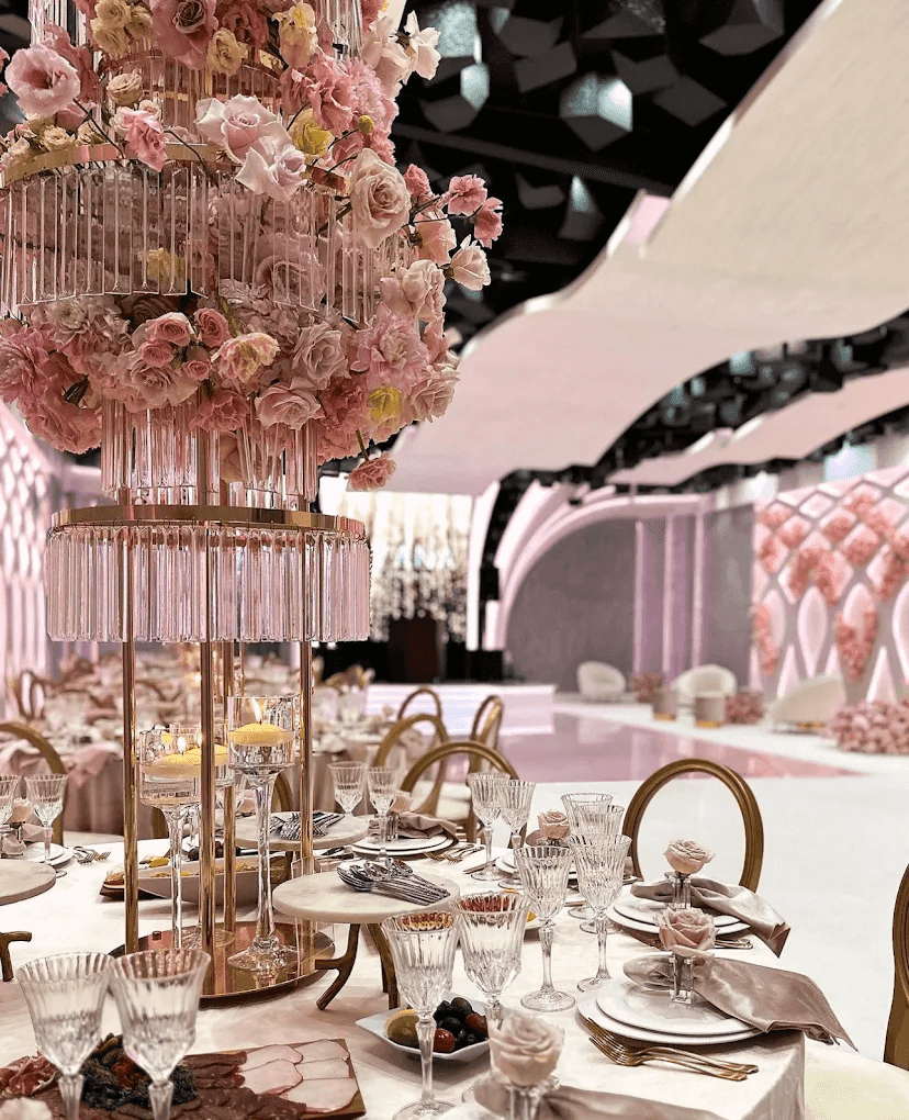 Elegant banquet table adorned with pink flowers, crystal glassware, and fine dining settings, set in a luxurious venue.