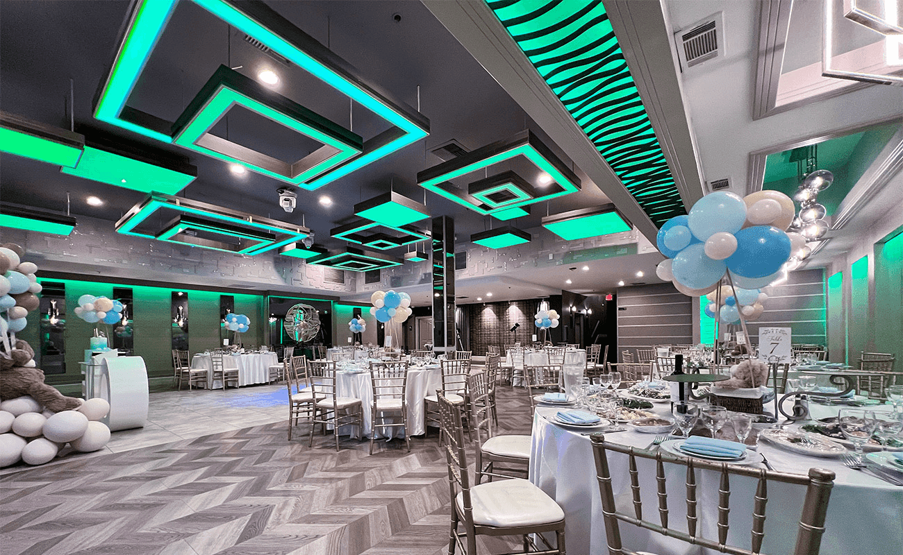 Elegant event space featuring green lighting, gold chairs, and balloon decorations in a modern setting.